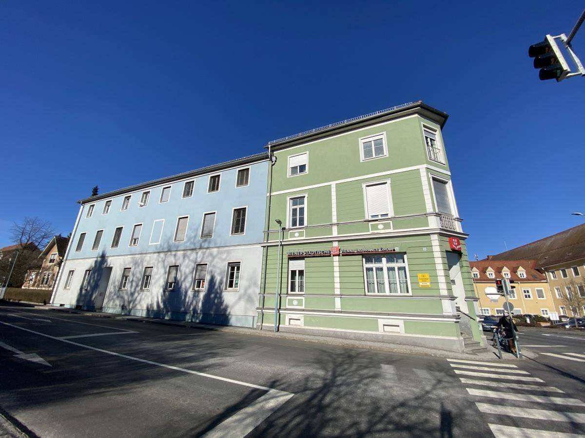 Eckgebäude mit markanter grüner und blauer Fassade an einer städtischen Straße gelegen.
