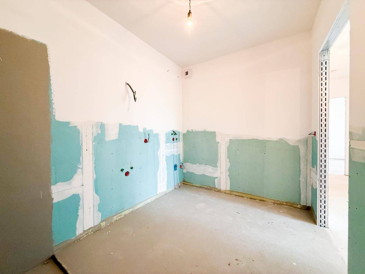 Rohbau eines Badezimmers mit sichtbaren Installationen und unfertigen Wänden, bereit für den Ausbau.