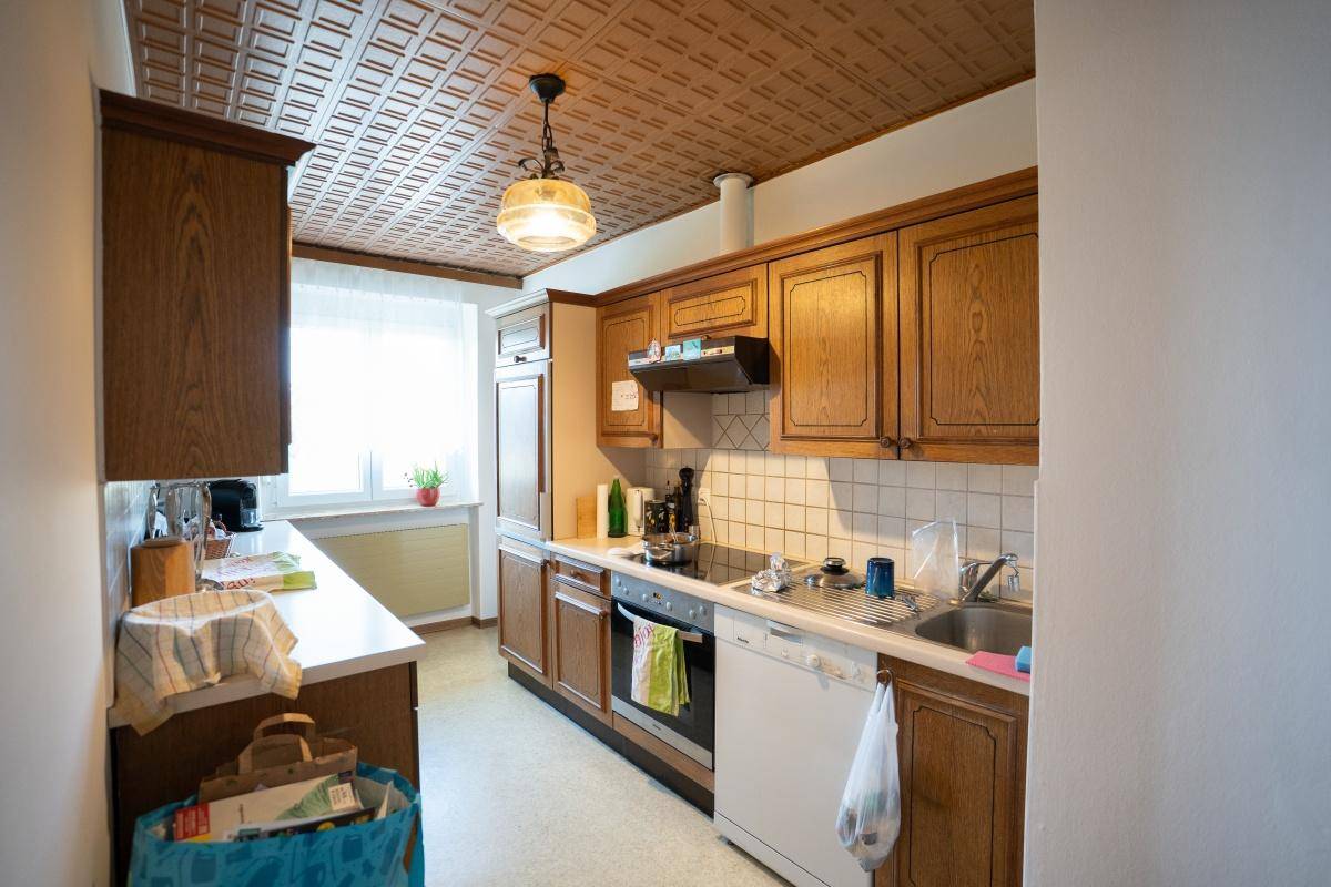 Traditionelle Küche mit Holzschränken, Fliesenboden und Deckenverkleidung.