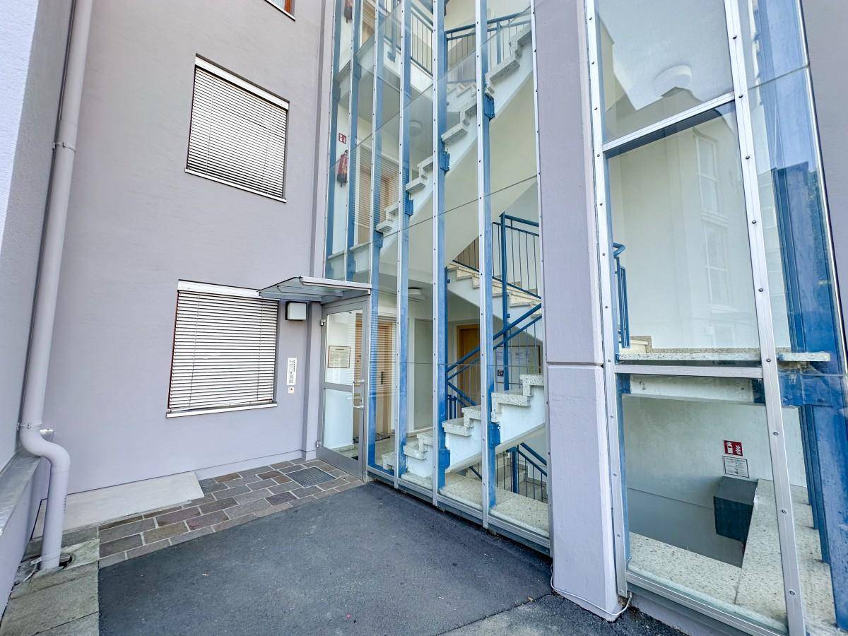 Eingangsbereich des Gebäudes mit Glasfassade für das Treppenhaus und Aufzug.