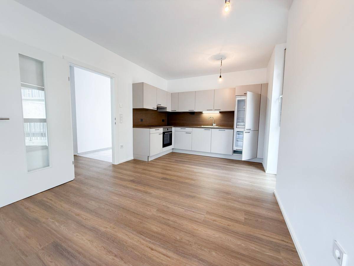 Moderne Einbauküche in hellem Design mit integrierten Geräten und Laminatboden.