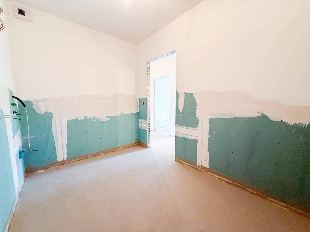 Badezimmer im Rohbau mit vorbereiteten Anschlüssen für Sanitäranlagen.