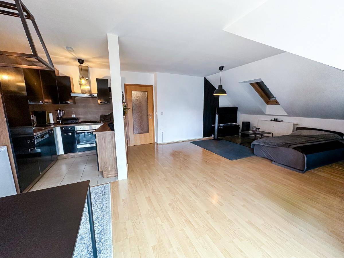 Offener Wohn- und Essbereich im Dachgeschoss mit integrierter Küche und Holzboden.