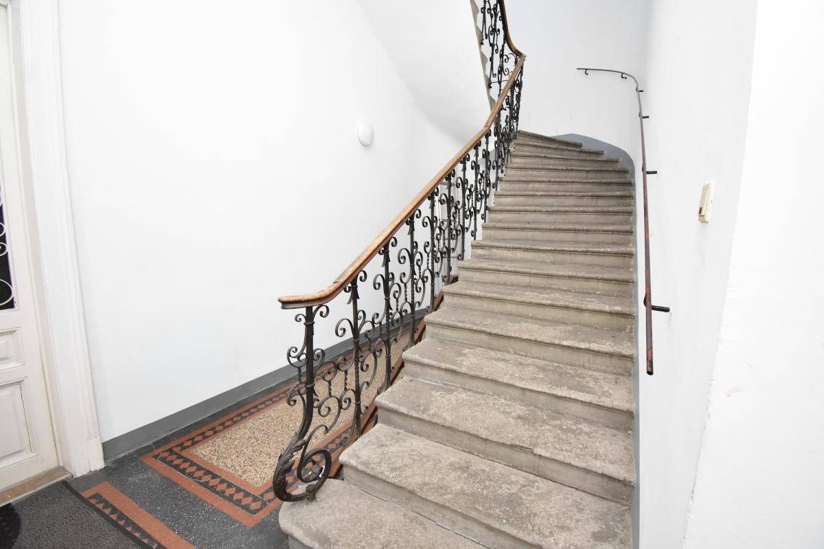 Historisches Treppenhaus mit schmiedeeisernem Geländer und Steinstufen.