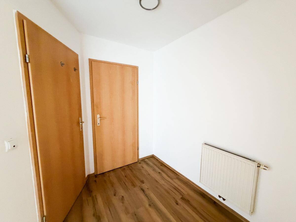 Heller Flurbereich mit zwei Holztüren, Heizkörper und durchgehendem Laminatboden.