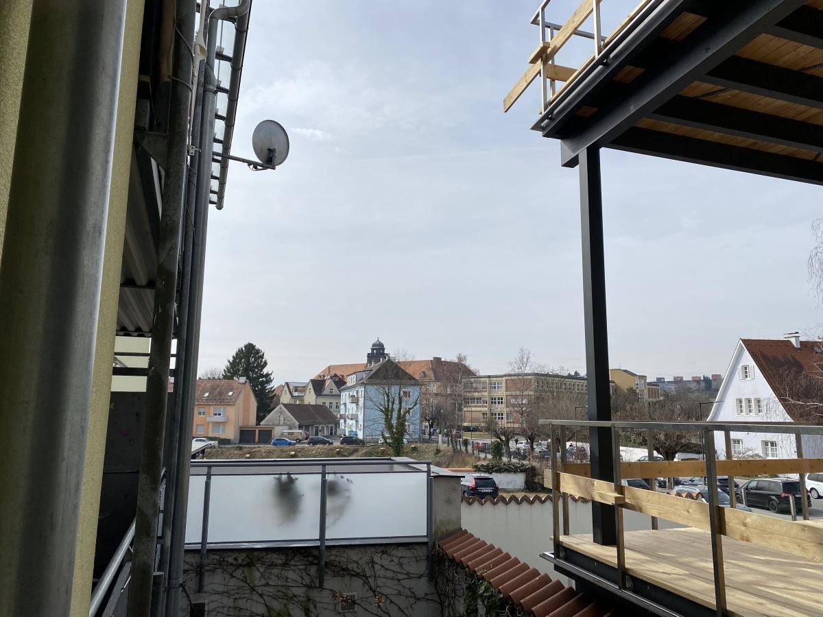 Blick von einem im Bau befindlichen Balkon auf eine Wohngegend mit Häusern und Bäumen.