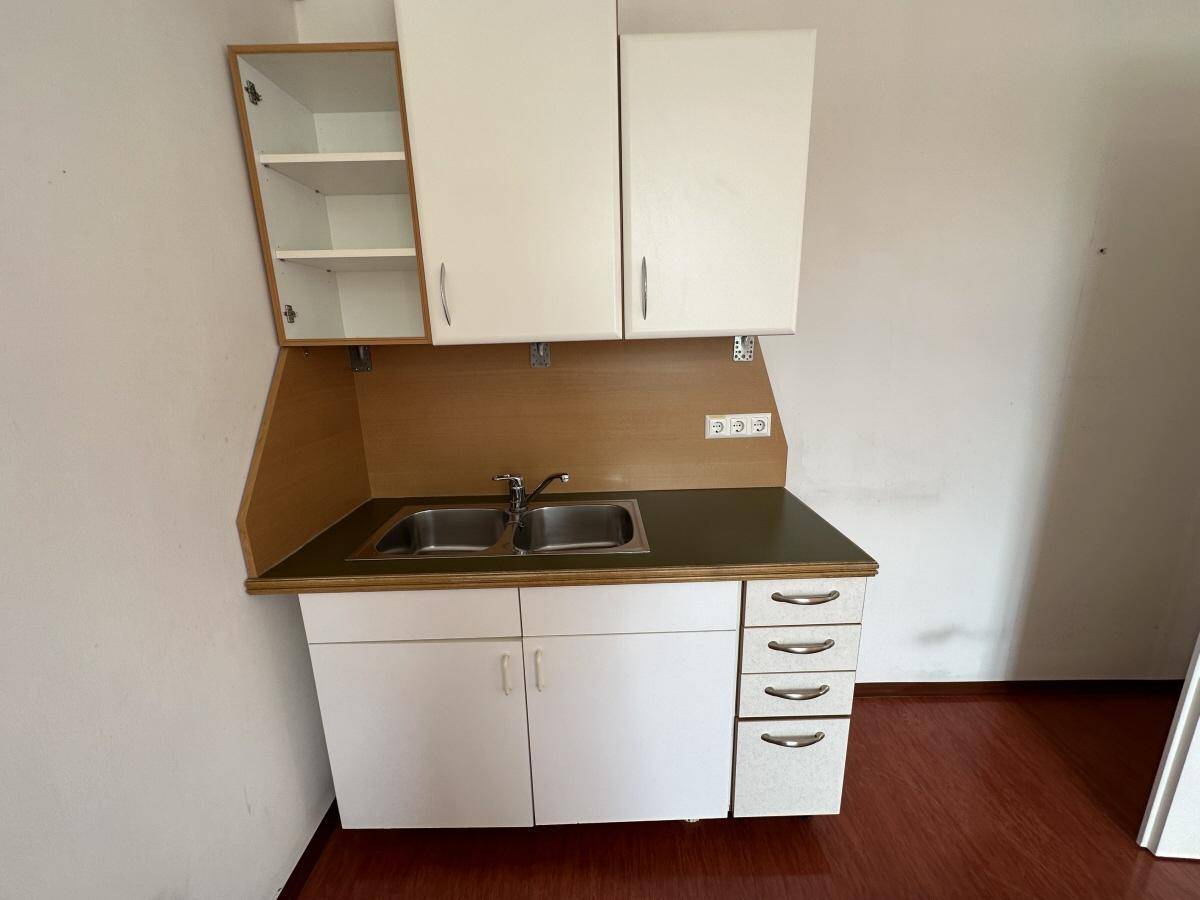 Einfache Küchenzeile mit Doppelspüle, weißen Schränken und Holz-Arbeitsplatte.