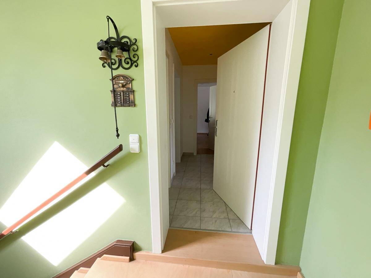 Eingangsbereich mit grün gestrichenen Wänden, Treppe und Zugang zu weiteren Räumen.