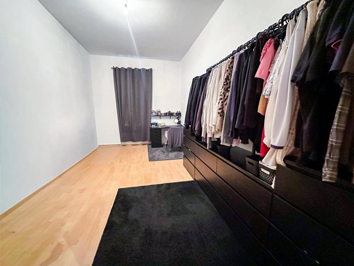 Geräumiger Ankleidebereich mit offener Kleideraufbewahrung und Holzboden.