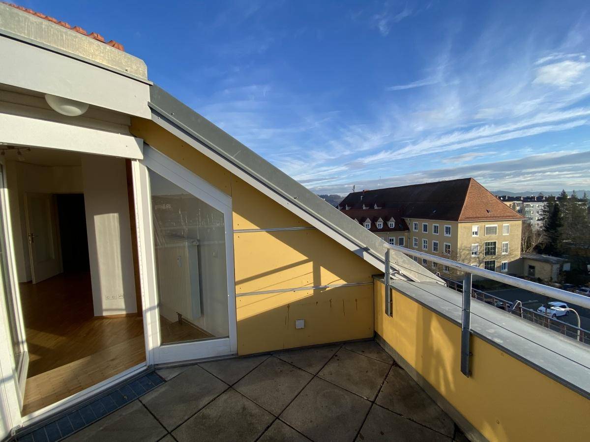 Sonnige Dachterrasse mit Fliesenboden und Panoramablick auf die Stadt und die umliegende Landschaft.