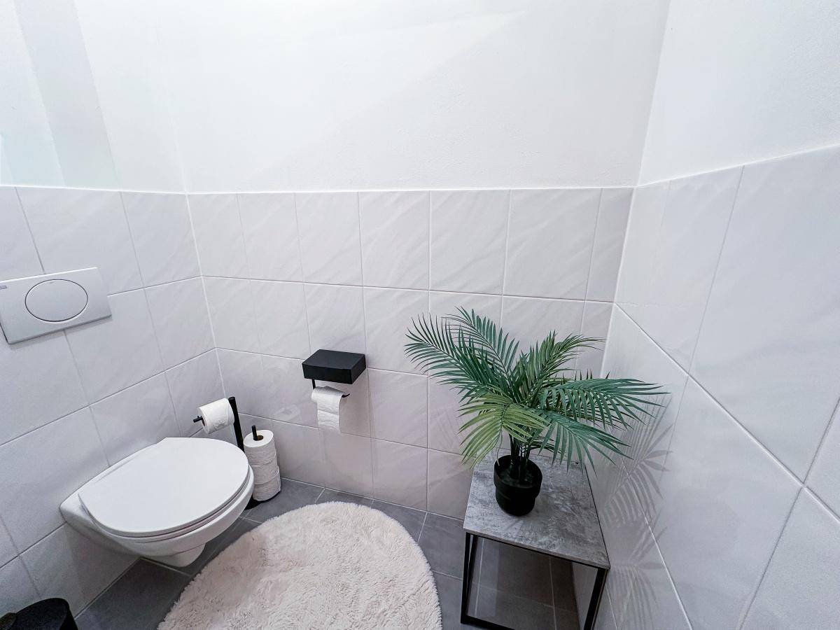 Kleines Gäste-WC mit Wand-WC, weißen Fliesen und minimalistischer Dekoration.