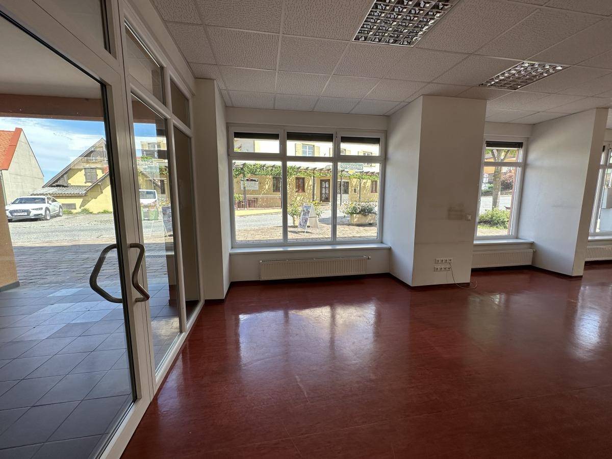Großer Gewerberaum mit viel Tageslicht durch die Fenster und Glastüren zum Eingangsbereich.