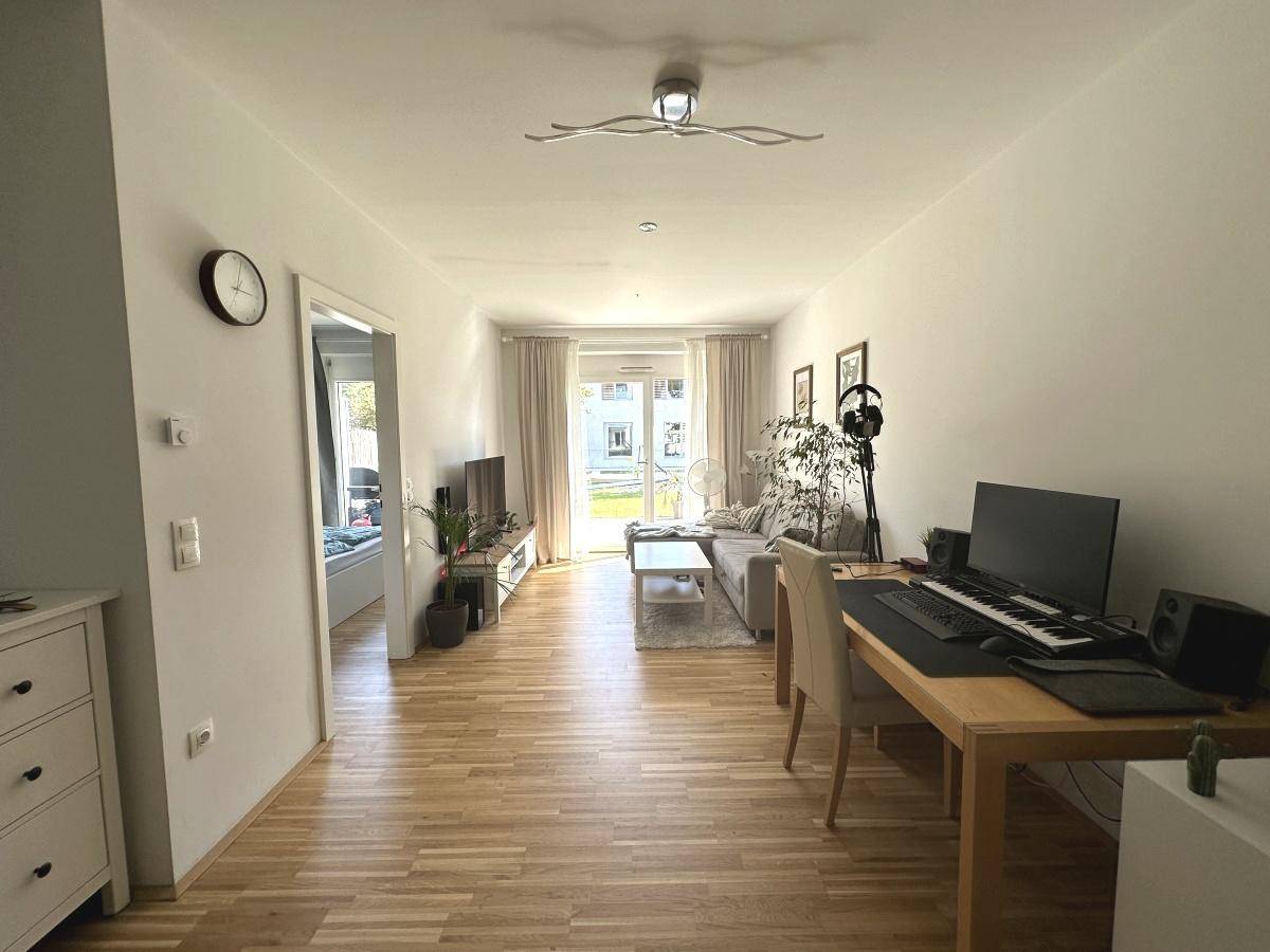 Geräumiges Wohnzimmer mit Holzboden, Sofa und Zugang zum Gartenbereich.