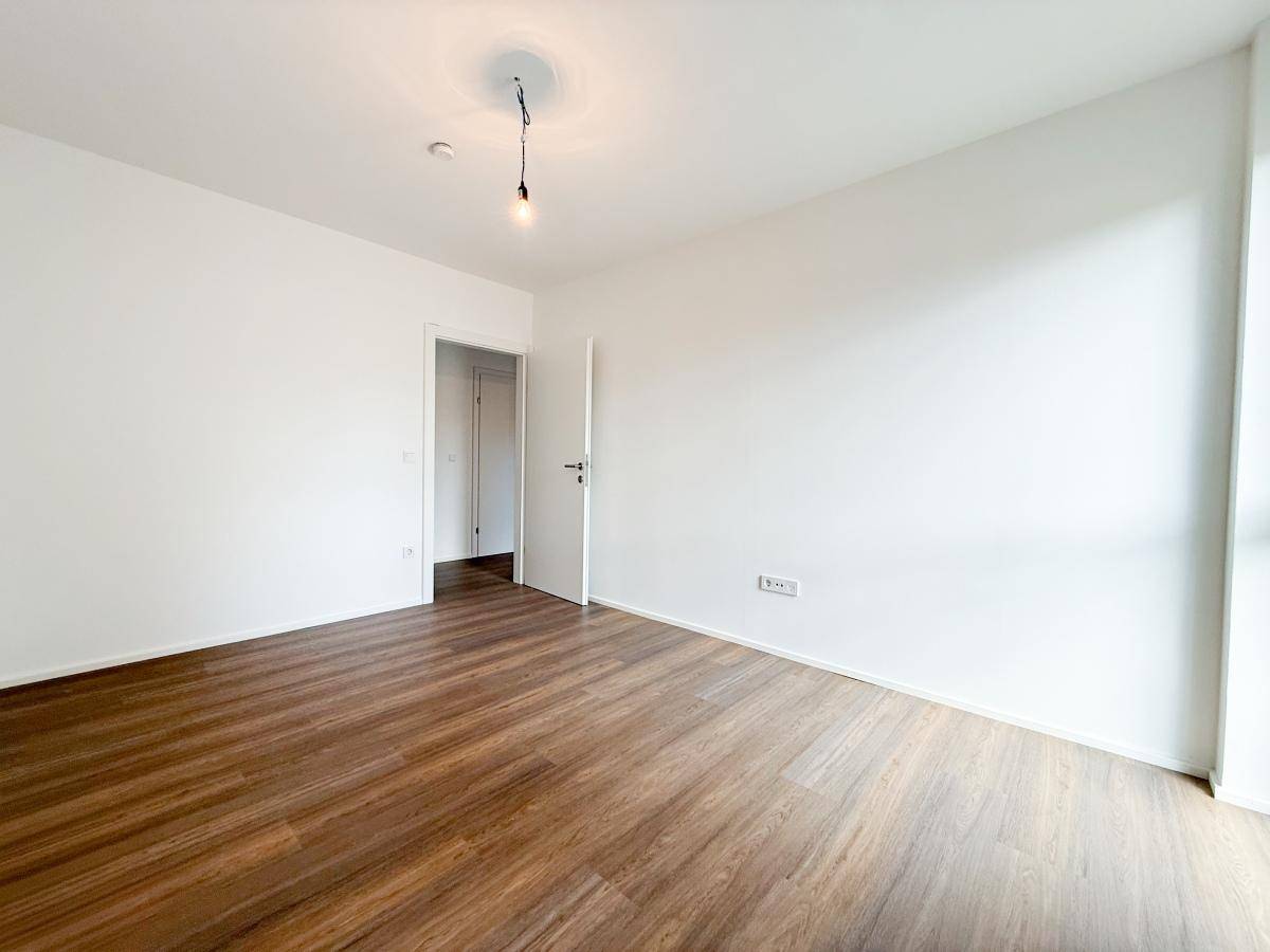Helles Schlafzimmer mit Laminatboden und weißer Tür, bietet eine neutrale Basis.
