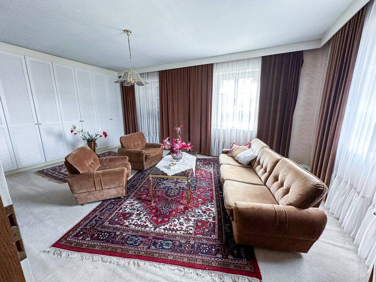 Geräumiges Wohnzimmer mit brauner Couch, Teppichboden und Einbauschränken.