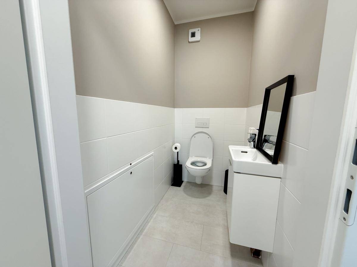 Modernes Gäste-WC mit wandhängender Toilette, kleinem Waschbecken und stilvollen Fliesen.