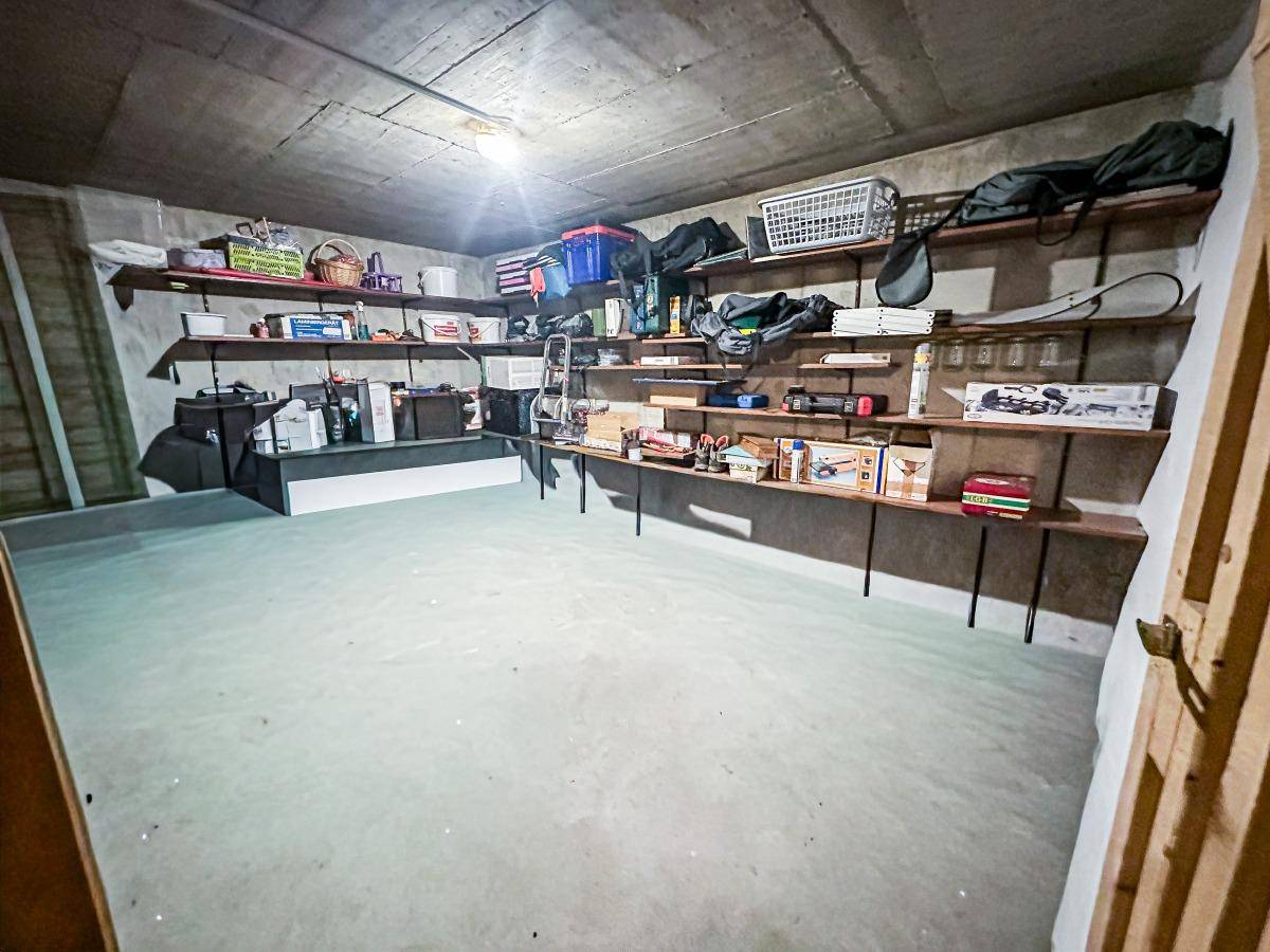 Geräumiger Kellerraum mit Regalen für Lagerung und Betonboden.