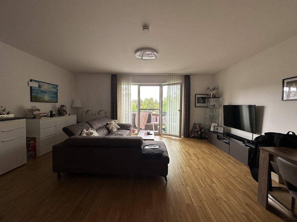 Gemütliches Wohnzimmer mit Sofa und TV-Bereich, direkter Zugang zum Balkon für frische Luft.