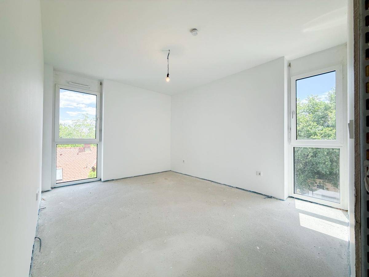 Helles Schlafzimmer im Rohbau mit zwei großen Fenstern und viel natürlichem Licht.