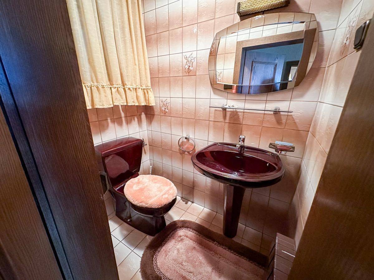 Gäste-WC mit dunklem Waschbecken und Toilette, gefliest in Rosa-Tönen.
