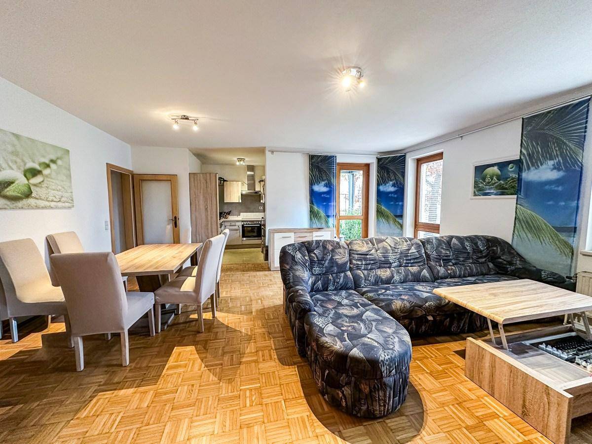 Offener Wohn- und Essbereich mit Parkettboden, Esstisch und bequemer Couch.