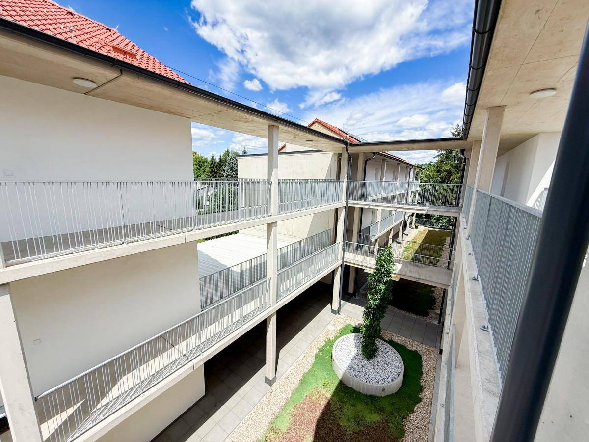Innenhof des Apartmentkomplexes mit zentraler Bepflanzung und Sitzgelegenheiten.