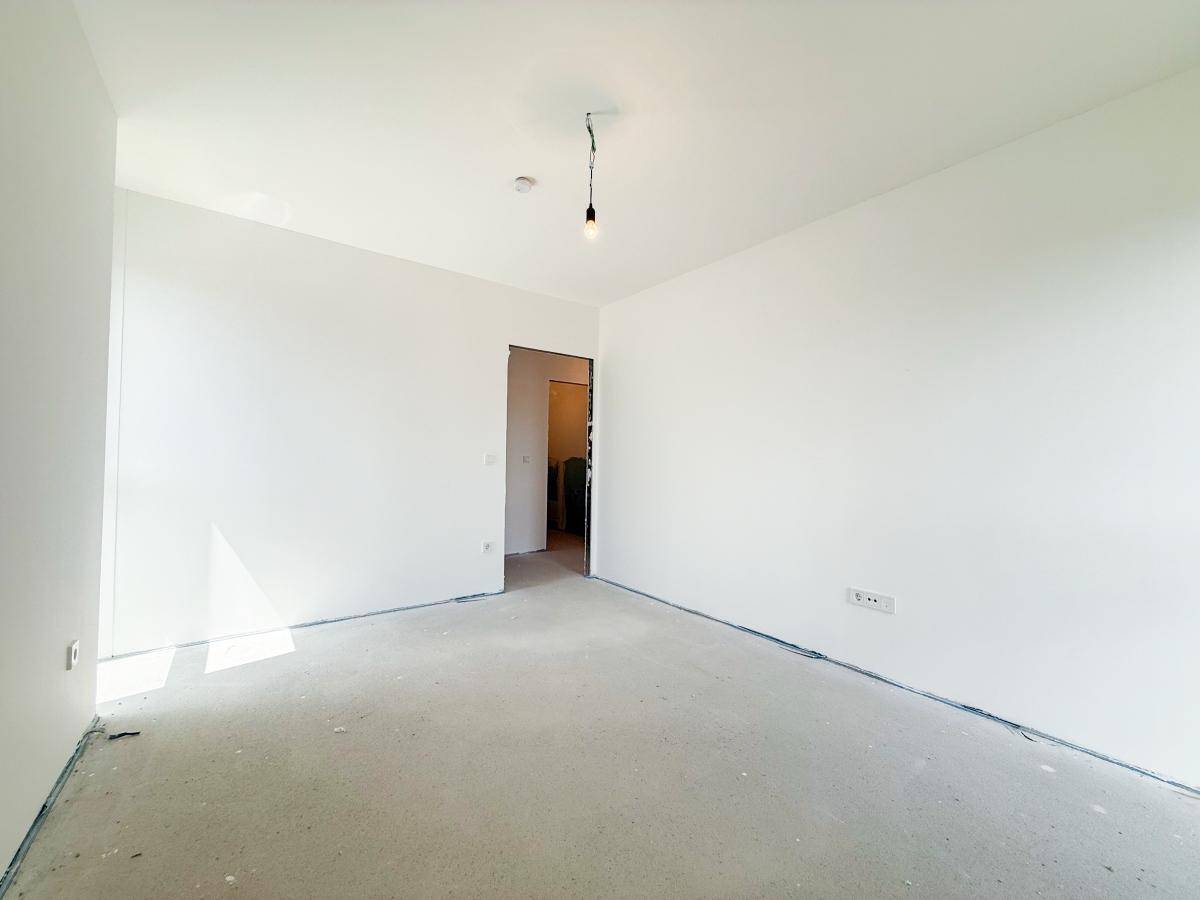 Heller, unmöblierter Raum mit weißen Wänden und Betonboden, bereit für den weiteren Ausbau.