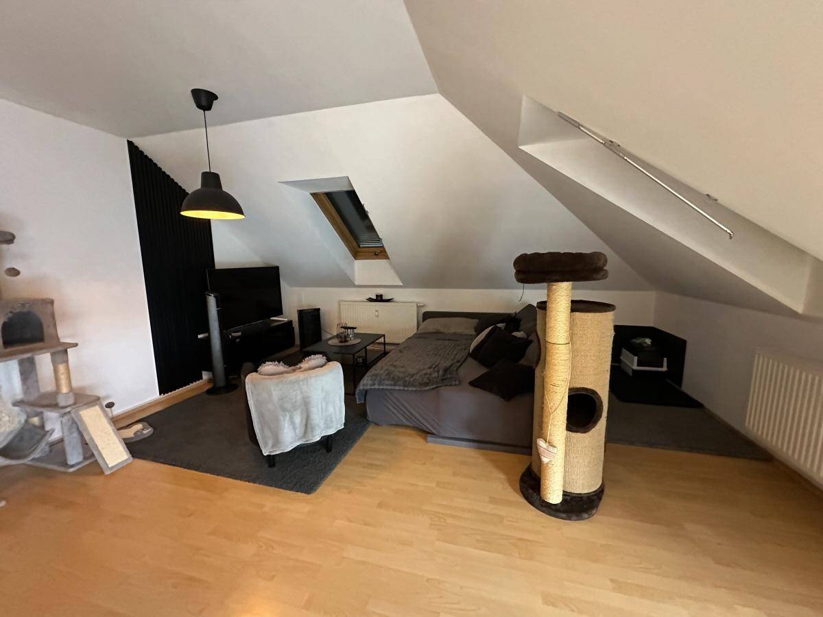 Gemütliches Dachgeschoss-Wohnzimmer mit Holzboden, Dachfenstern und Unterhaltungselektronik.