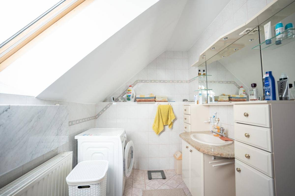 Badezimmer im Dachgeschoss mit Waschtisch, Spiegelschrank und Waschmaschine.