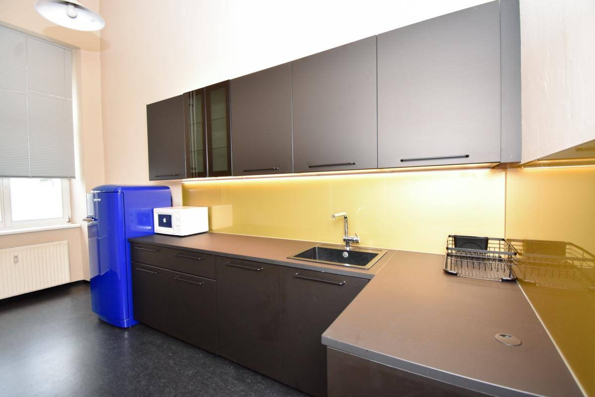 Moderne Küchenzeile mit dunklen Schränken, gelber Rückwand und einem auffälligen blauen Retro-Kühlschrank.