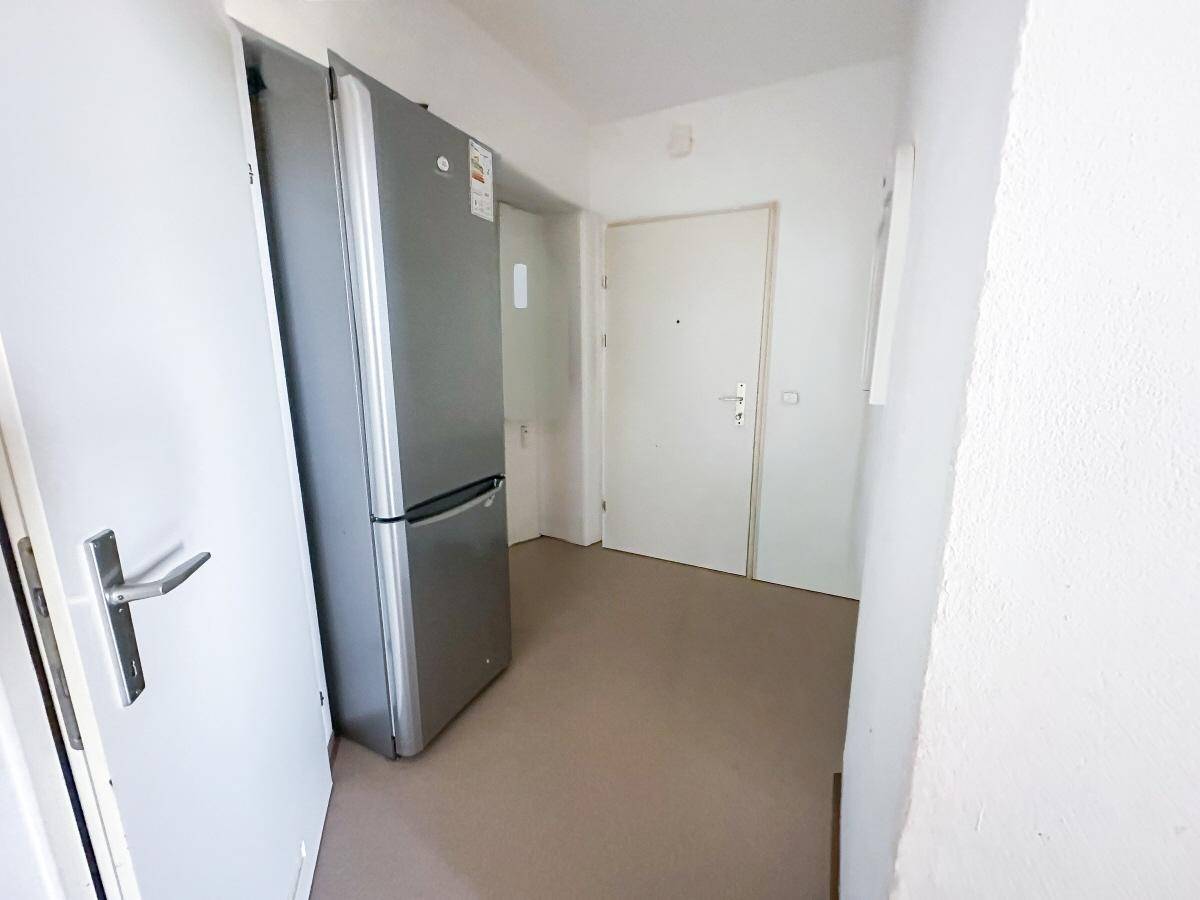 Eingangsbereich mit großem Kühlschrank und Zugang zu weiteren Räumen.