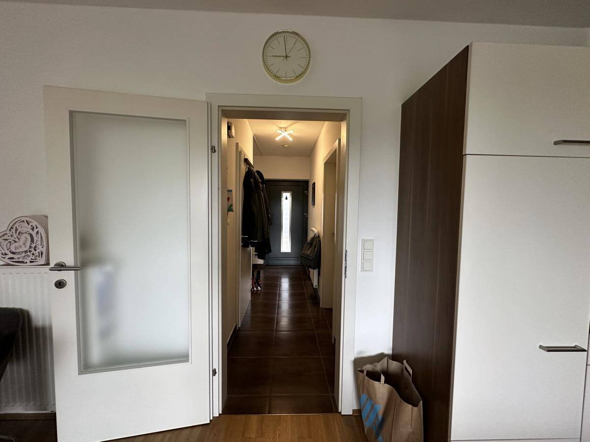 Blick vom Wohnbereich in den Flur mit Milchglastür, verbindet die Wohnräume elegant.
