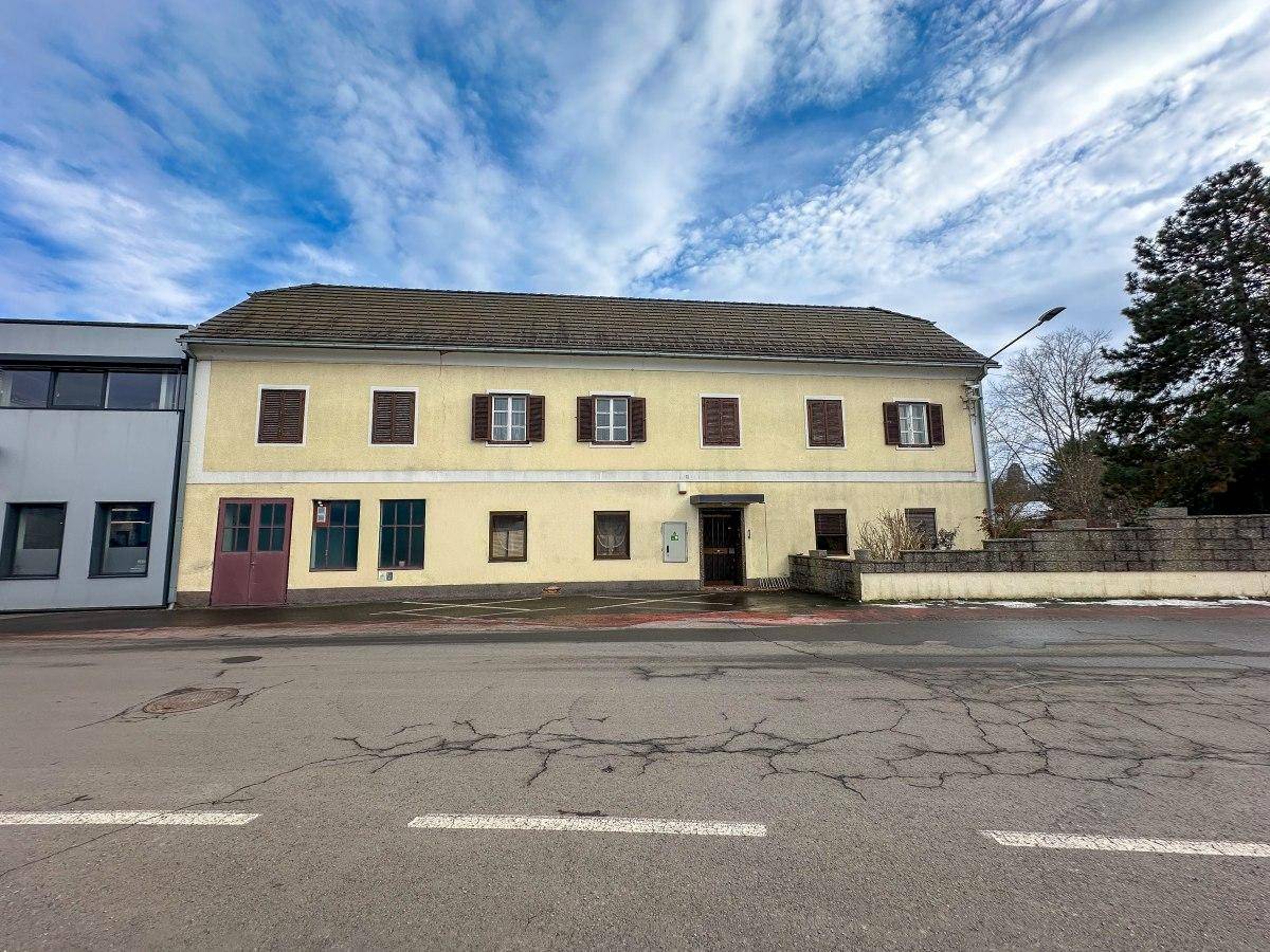 Ansicht des Wohnhauses von der Straße mit gelber Fassade und braunem Dach.