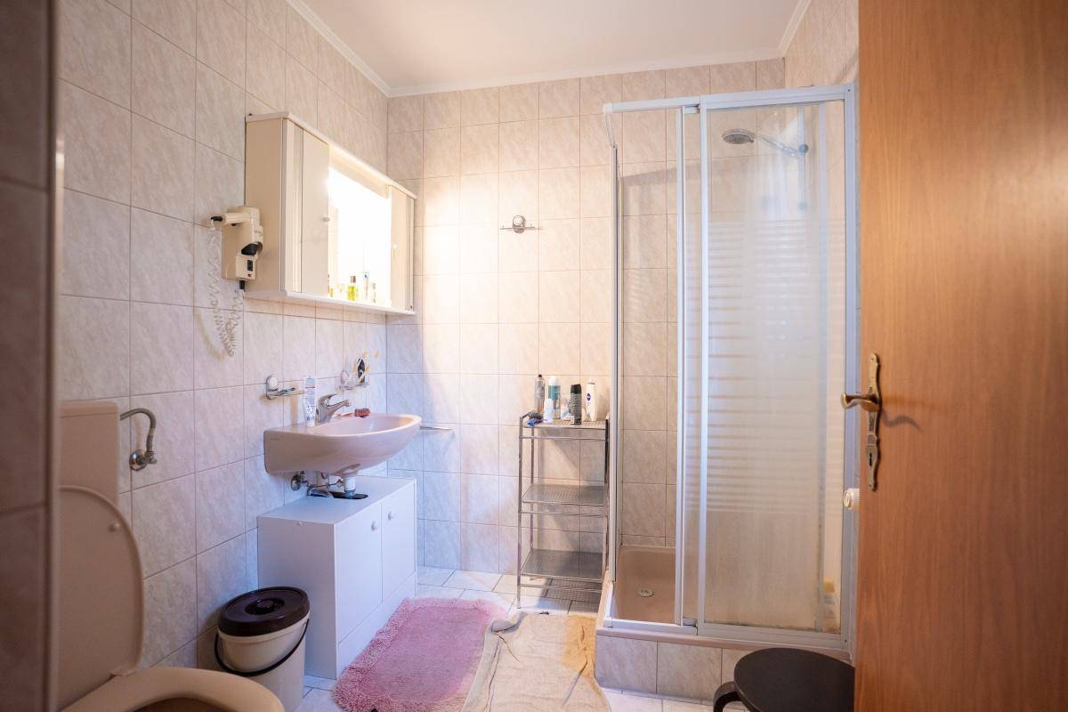 Helles Badezimmer mit Duschkabine, Waschbecken und WC, in gutem Zustand.