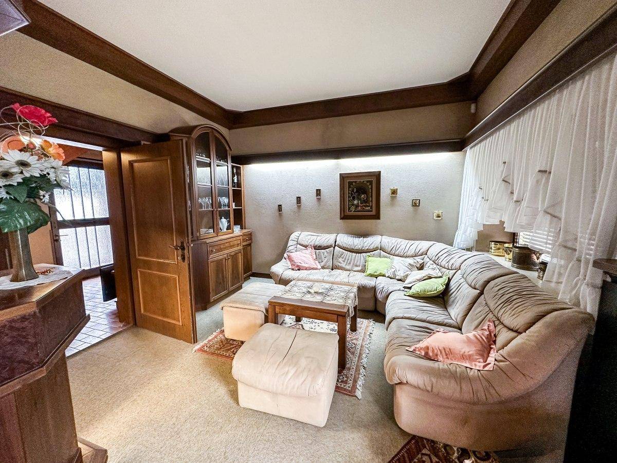Gemütliches Wohnzimmer mit großer Eckcouch, Teppichboden und traditioneller Einrichtung.