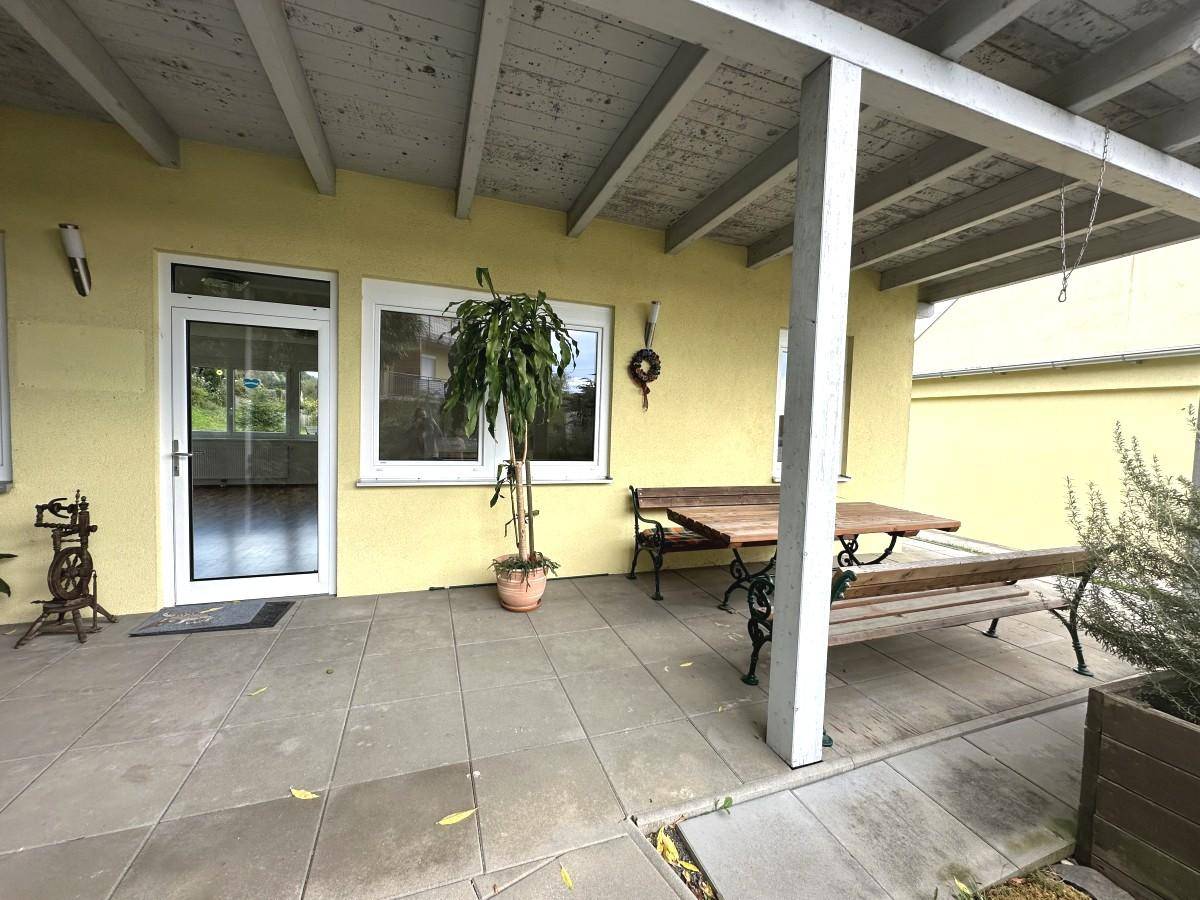 Überdachte Terrasse mit Fliesenboden und Holzbänken, ideal für entspannte Stunden im Freien.