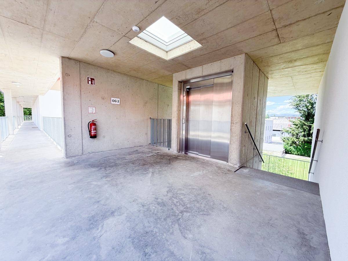 Moderner Aufzugsbereich in einem Wohngebäude mit viel Tageslicht durch ein Oberlicht.