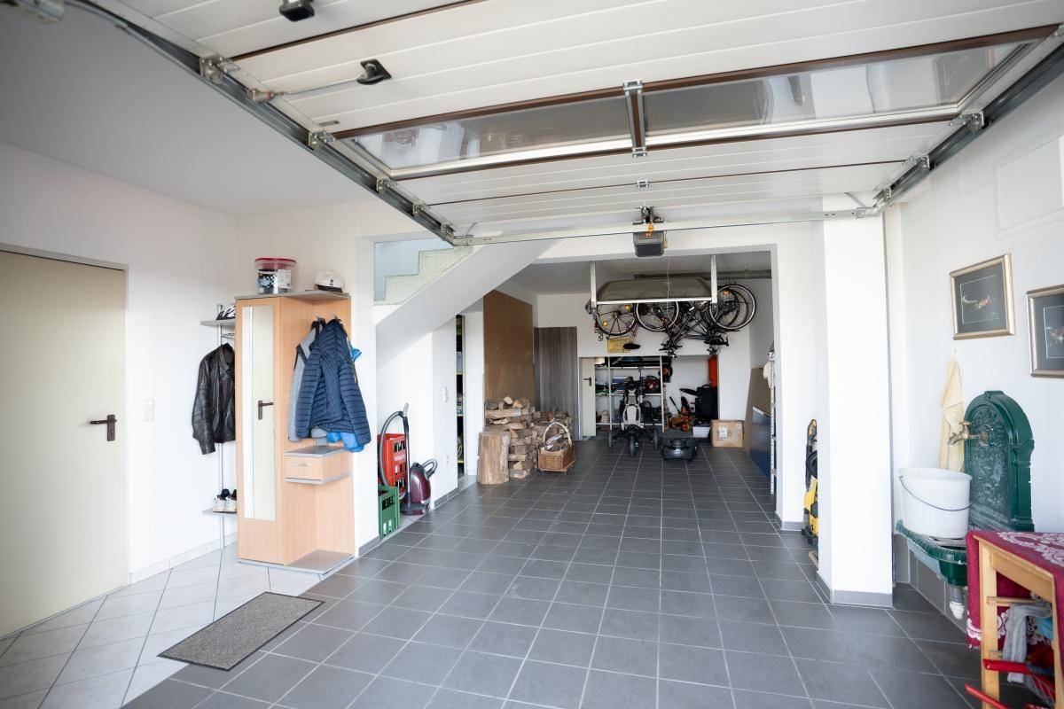 Geräumige Garage mit Fliesenboden, Stauraum und Zugang zu weiteren Bereichen.