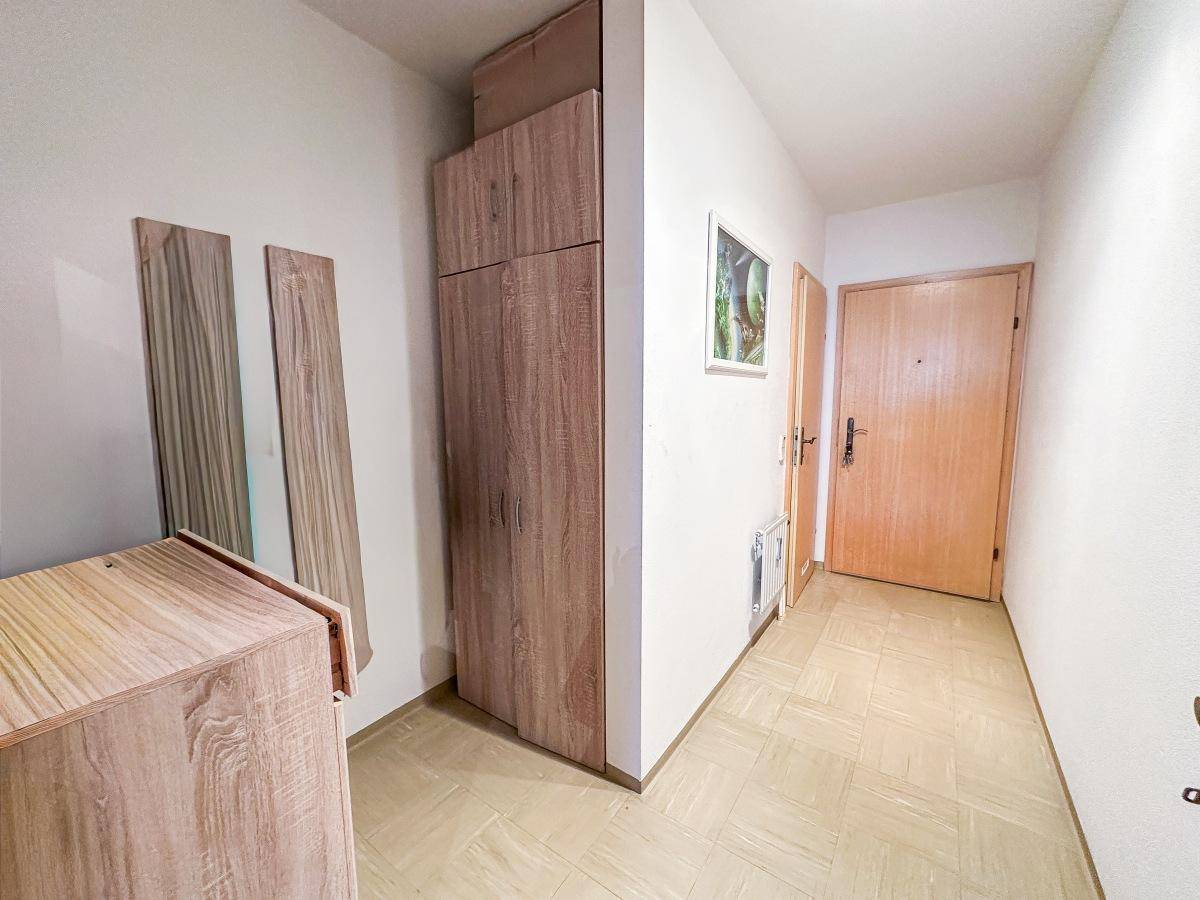 Eingangsbereich mit Garderobenschrank, Spiegel und hellem Laminatboden.