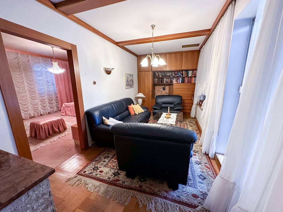 Wohnzimmer mit Ledersofas, Parkettboden und Bücherregal.