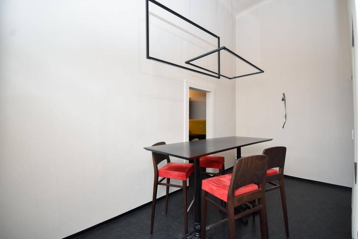 Essbereich mit einem langen schwarzen Tisch und roten Stühlen unter modernen Hängelampen, bietet stilvollen Komfort.