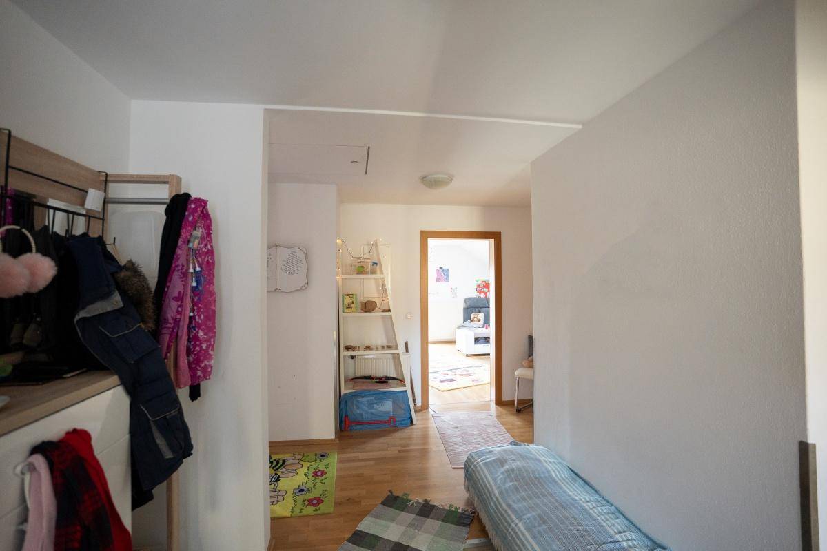 Heller Flur mit Garderobe und Zugang zu weiteren Räumen, mit Holzparkettboden.