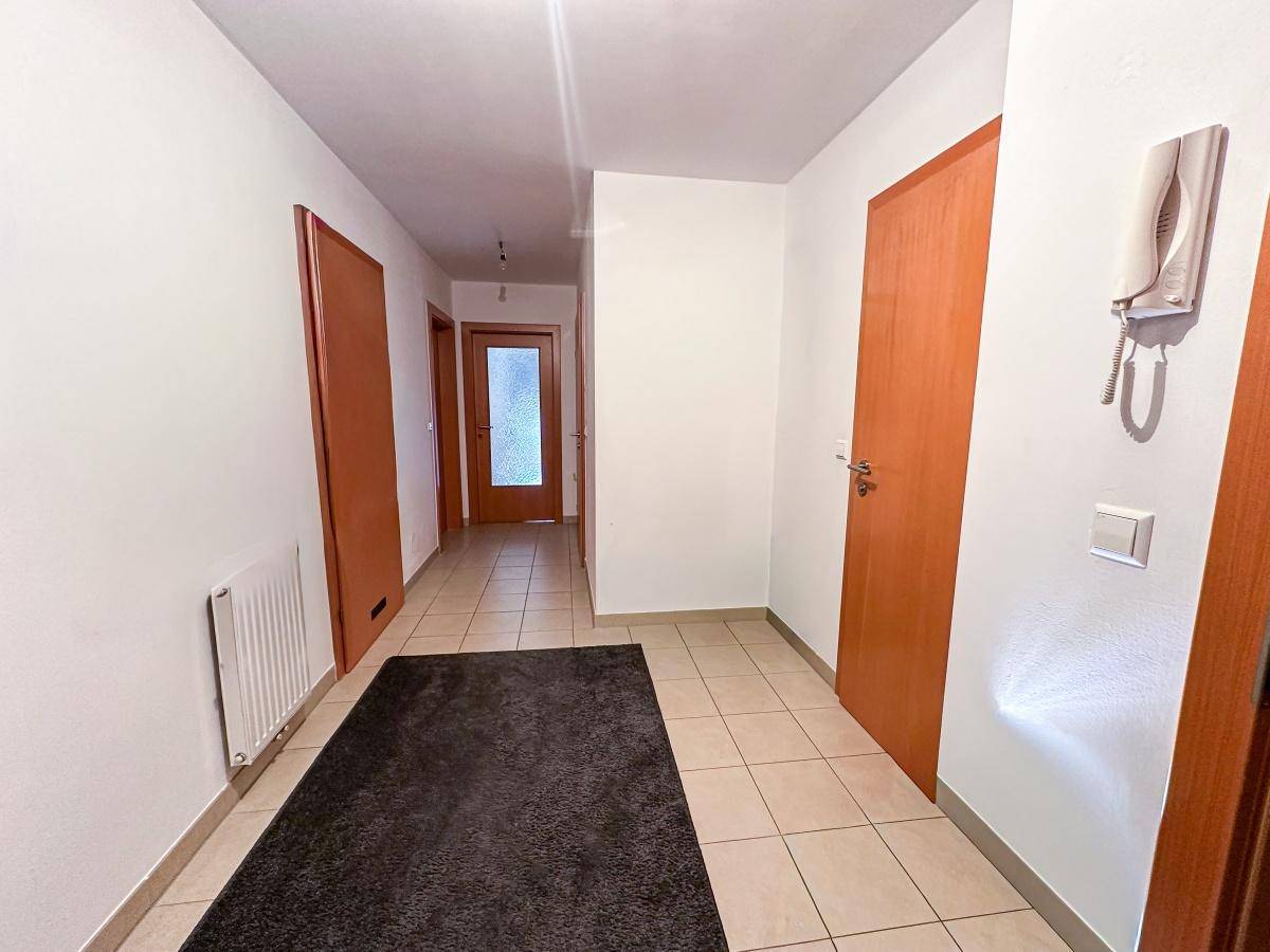 Heller Flur mit Fliesenboden und Holztüren, der zu weiteren Räumen führt.