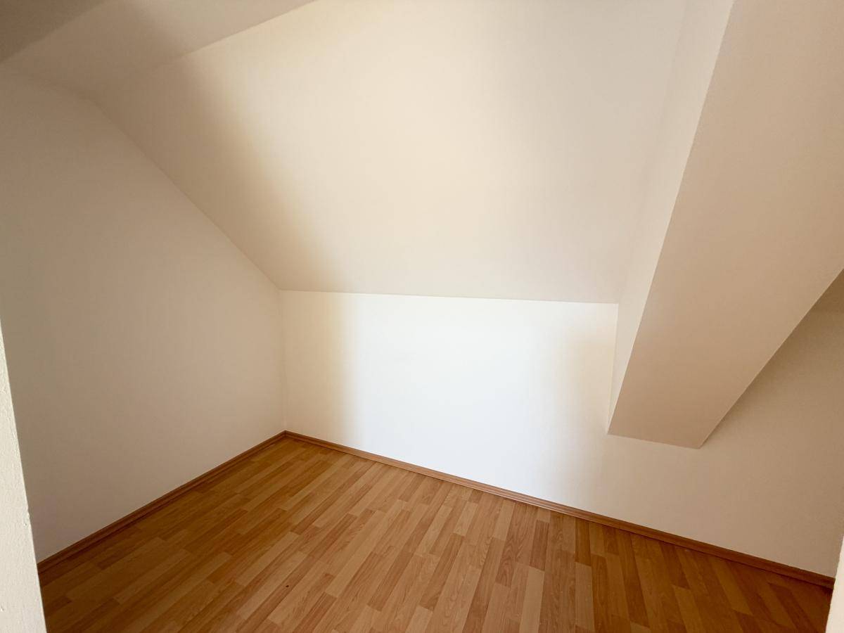 Kleiner Abstellraum im Dachgeschoss mit Laminatboden und schrägen Wänden, ideal für zusätzlichen Stauraum.