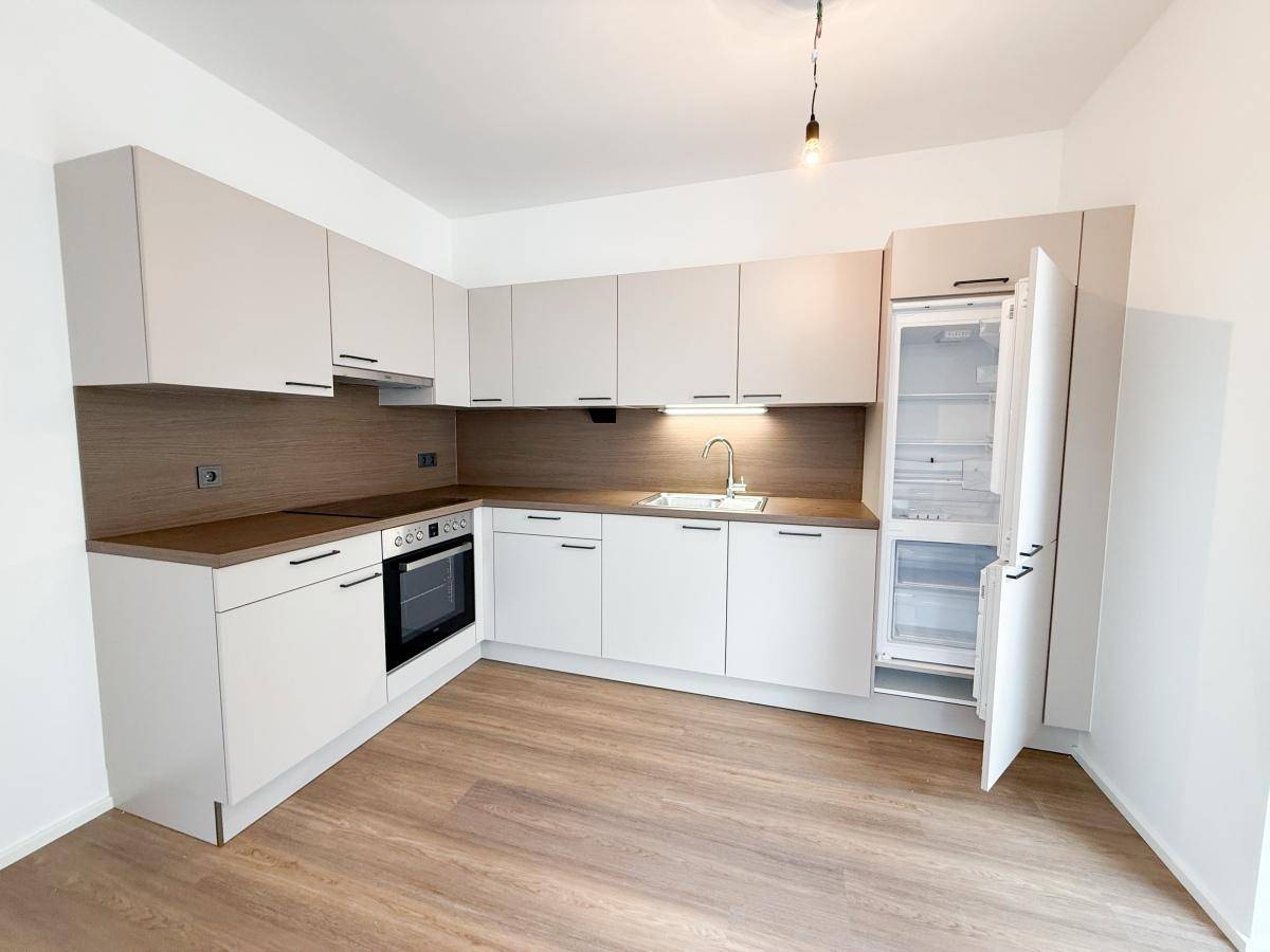 Moderne Einbauküche in hellem Design mit integrierten Geräten und Laminatboden.