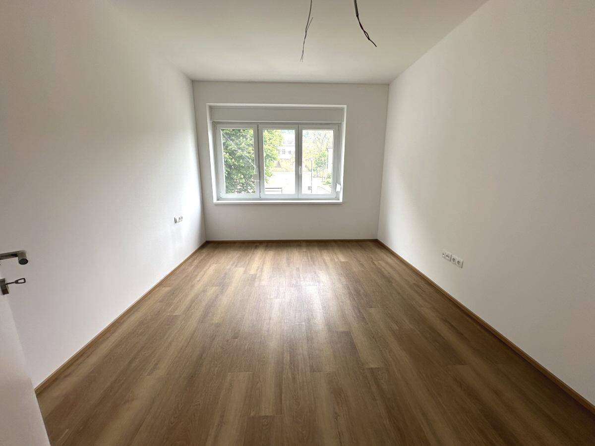 Helles, unmöbliertes Zimmer mit Laminatboden und Fenster, ideal als Schlaf- oder Arbeitszimmer.