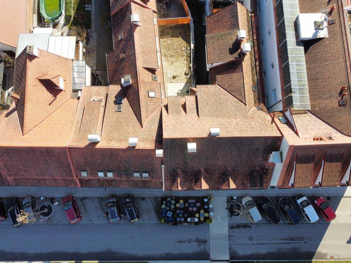 Draufsicht auf die Dächer mehrerer Gebäude und einen Parkplatz mit vielen Autos.