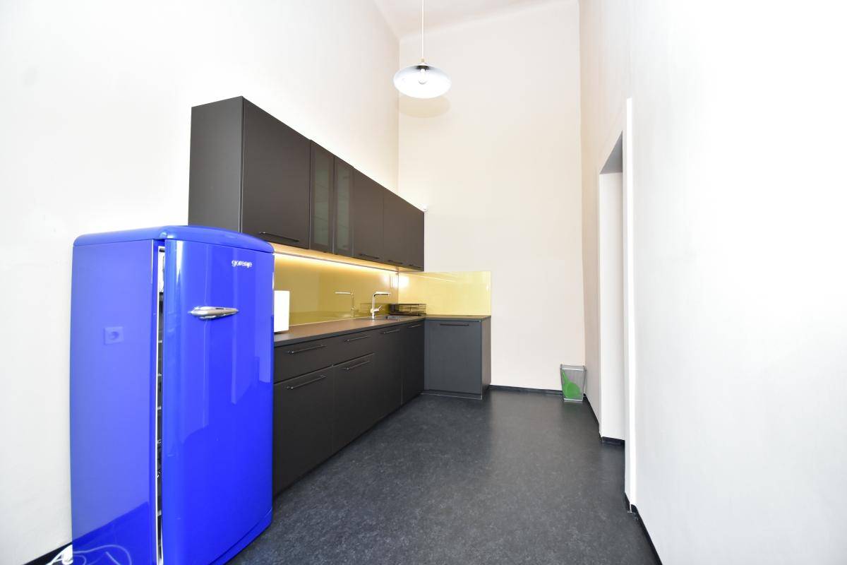 Moderne Küchenzeile mit dunklen Schränken und einem auffälligen blauen Kühlschrank in einem hellen Raum.