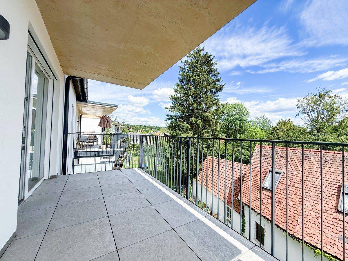 Heller Balkon mit Fliesenboden und weitem Blick über die Dächer und grüne Umgebung.