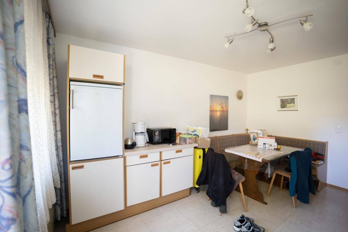 Kleine Küche mit Kühlschrank, Mikrowelle und gemütlicher Essecke am Fenster.